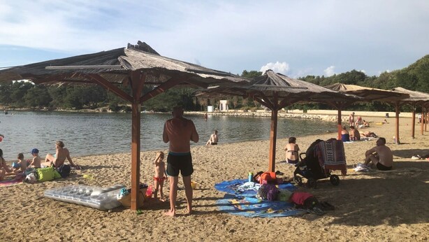 Una playa con sombrillas y gente relajándose.