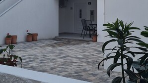 A two-story building with a tiled roof, a staircase leading to the upper floor, and a small outdoor seating area with a table and chairs. - House Dalmatika Zaton (Nin)