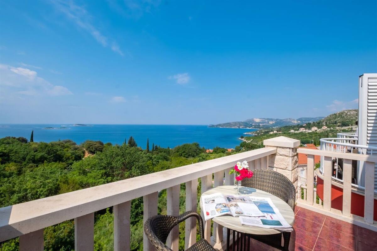 A balcony with a view of the sea, a table with magazines, and a wicker chair.