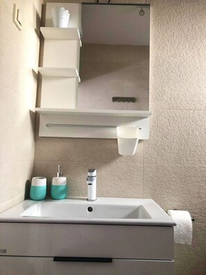 A bathroom with a white sink, two soap dispensers, a mirror, and a towel rack. - Apartments Mare Family Only (Kolan)