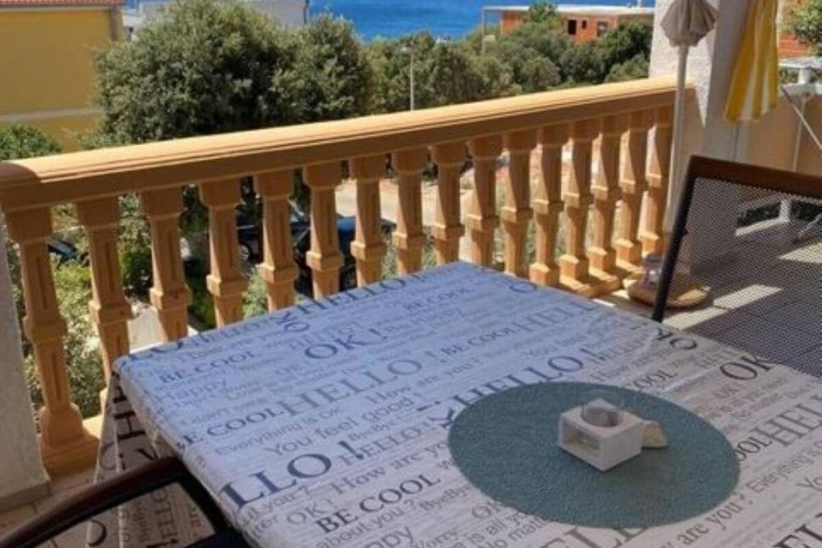 A balcony with a view of the sea, a newspaper spread on the floor, and a small object on the newspaper.