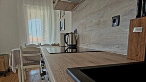 A modern kitchen with wooden countertops, a stainless steel kettle, and a small sink. - Apartments Mare Family Only (Kolan)