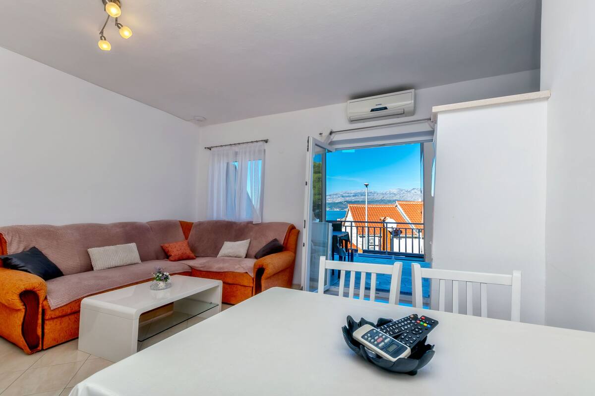 Una sala de estar moderna con un sofá, una mesa de centro y un balcón con vistas a edificios.