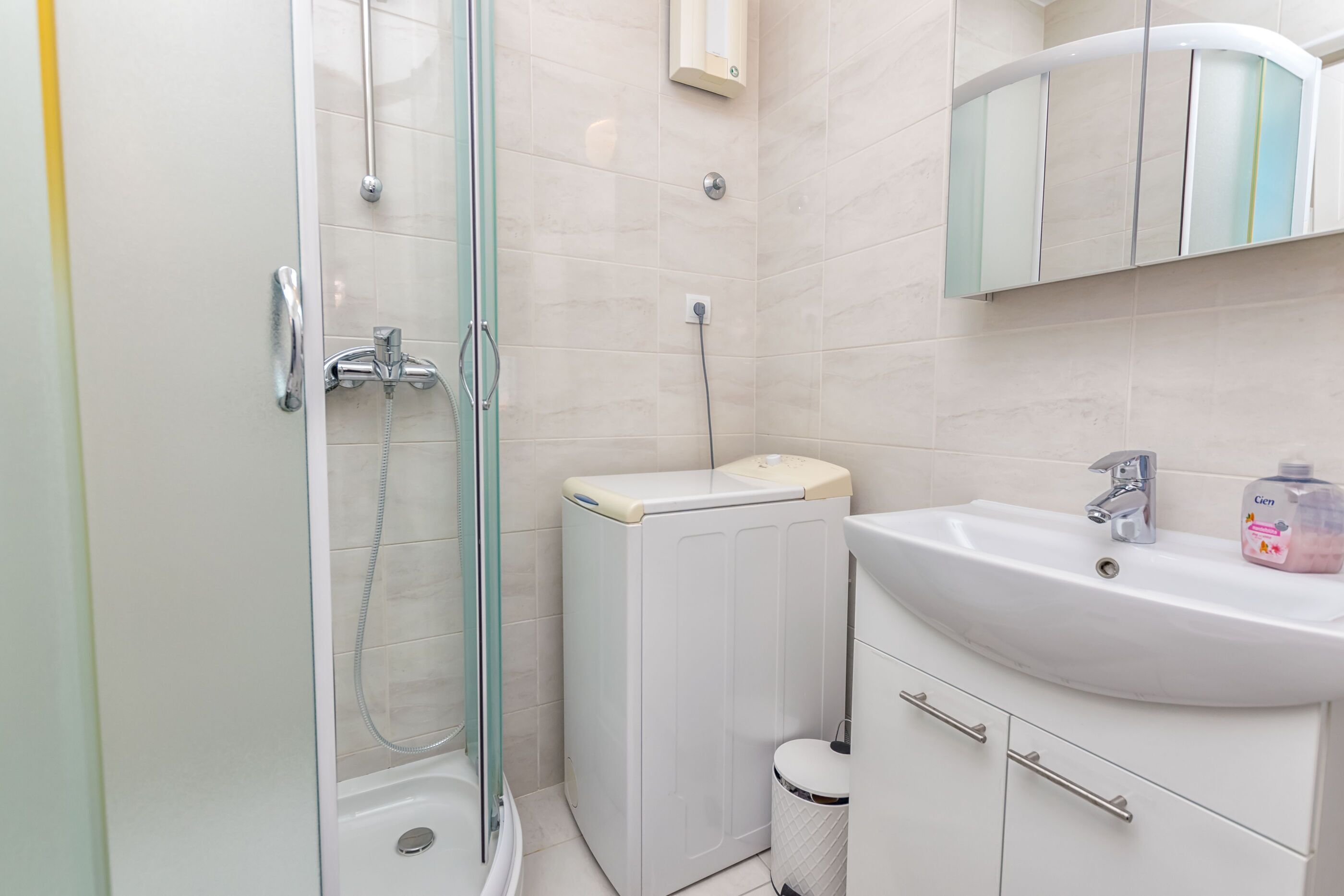 A modern bathroom with a glass-enclosed shower, a white sink, and a toilet.