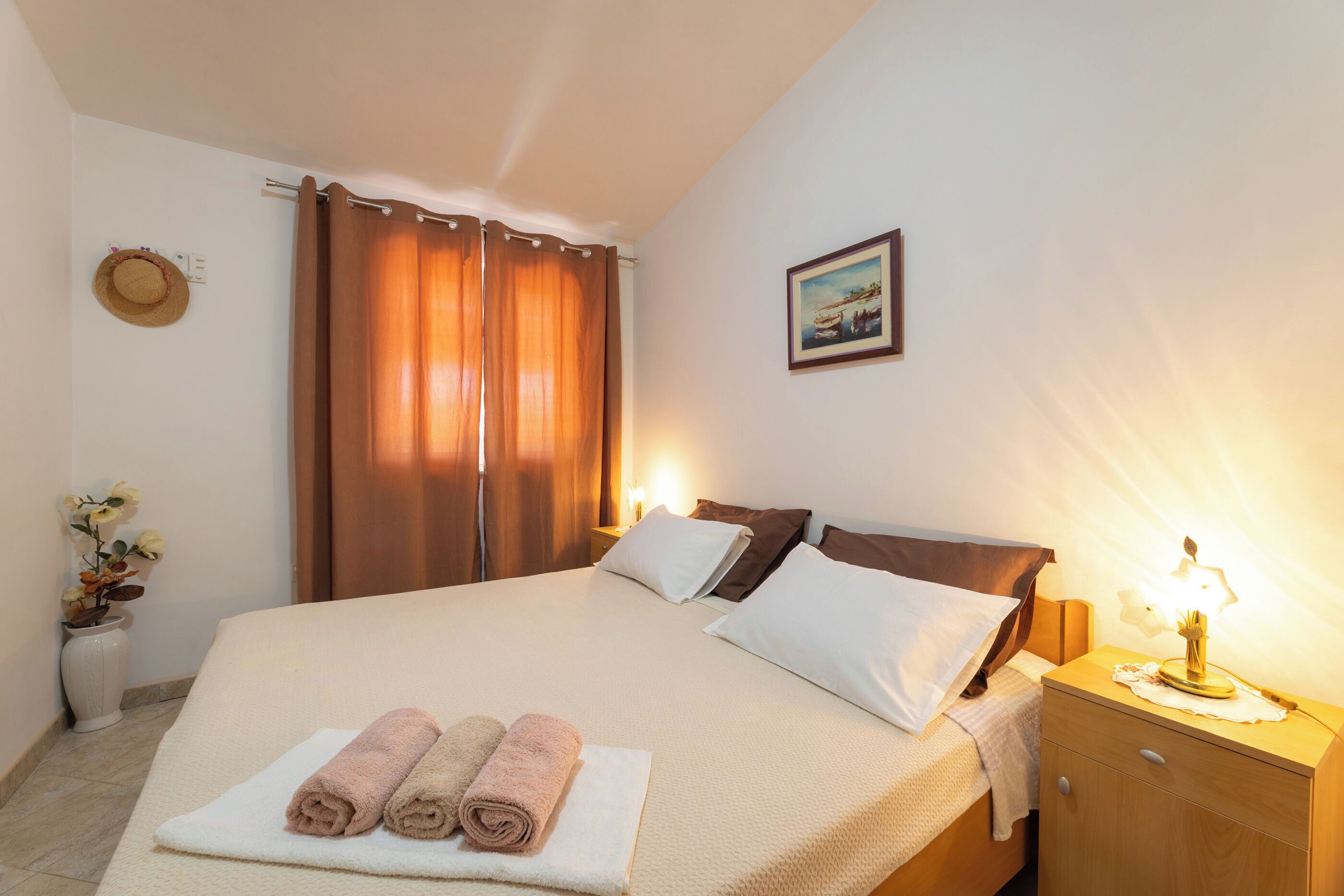 A neatly made bed with pillows, a bedside lamp, and a framed picture on the wall.