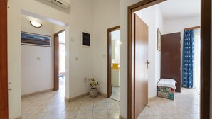 A hallway with a tiled floor, a vase with flowers, and a small bench. - Apartments Ivo (Kastela)