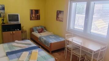 A room with two beds, a desk, a chair, a television, and artwork on the walls.