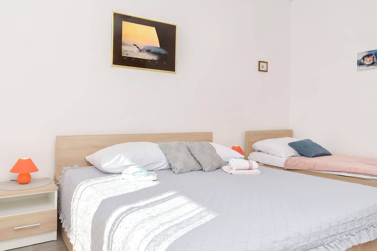 A bedroom with a bed, pillows, a nightstand, a lamp, and a framed picture on the wall.