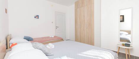 A bedroom with a large bed, a wardrobe, a bedside table, and a mirror.