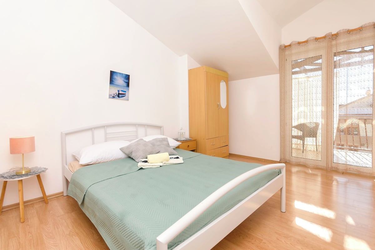 A neatly arranged bedroom with a bed, bedside table, lamp, and a wardrobe.