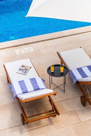 Two sun loungers with cushions, a small table with two glasses of orange juice, and a pool in the background. - House Villa Gold (Supetar)