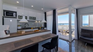 Une cuisine moderne équipée d’un four à micro-ondes encastré, d’une machine à café et d’un coin repas offrant une vue sur la mer.