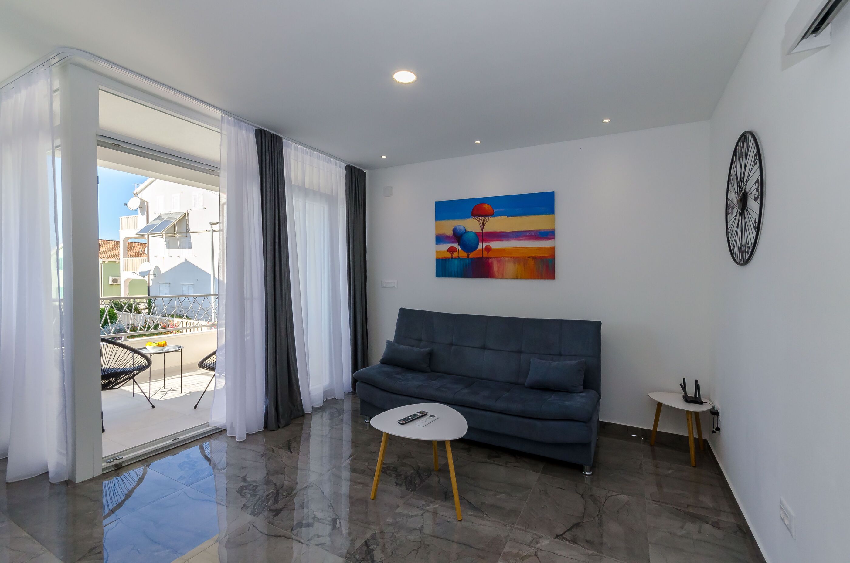 A modern living room with a grey sofa, a small round table, and a painting on the wall.