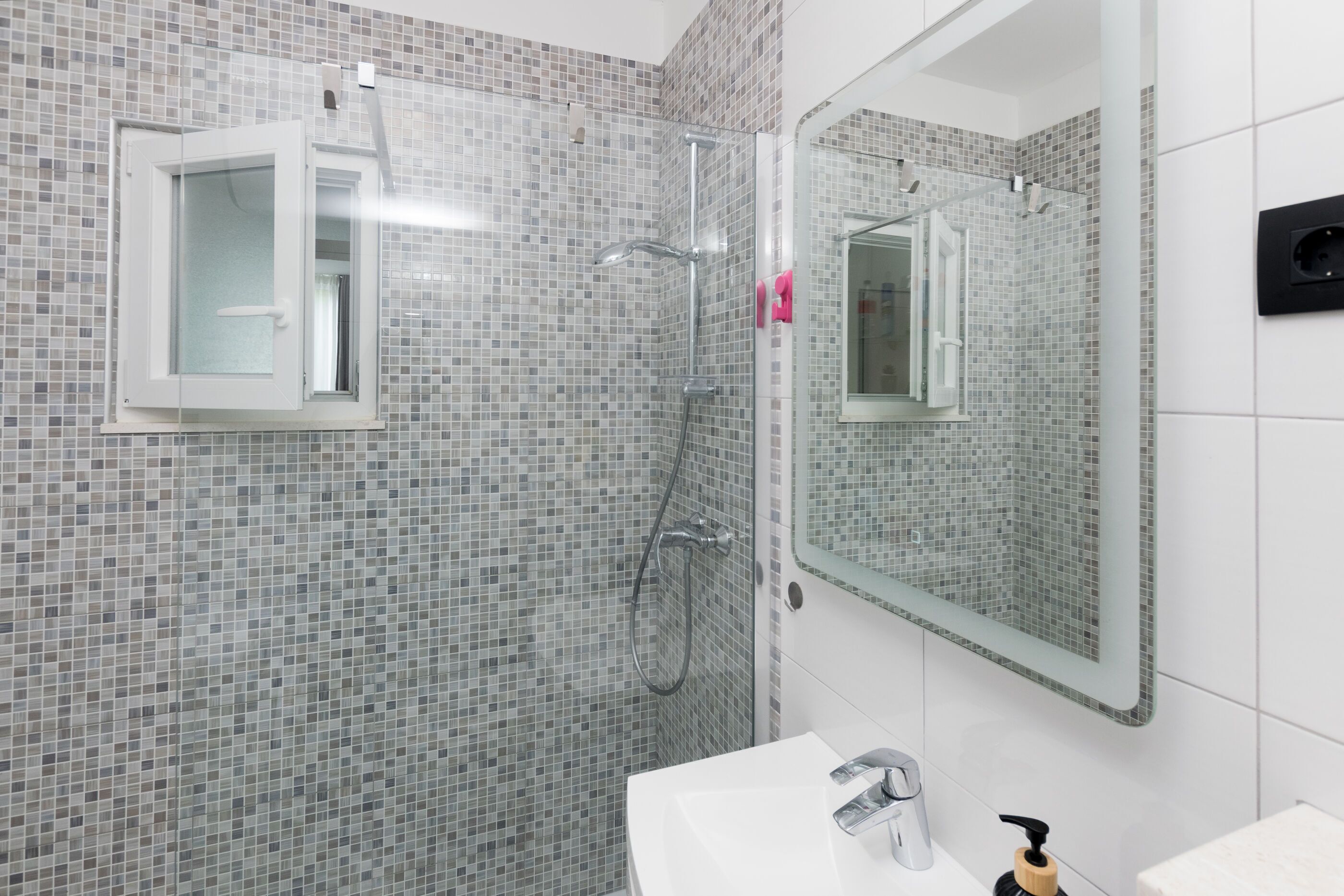 A bathroom with a shower, a sink, and a mirror.