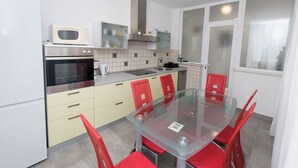 Une cuisine moderne avec une table à manger en verre, des chaises rouges et des appareils électroménagers en acier inoxydable.