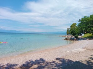 A beach with clear water, pebbly shore, and trees. - Apartments Rosuje (Omisalj)