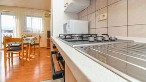 Una cocina moderna con estufa a gas, microondas y fregadero. Hay una zona de comedor con mesa y sillas.