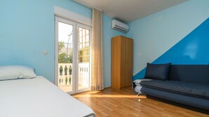 Un dormitorio con cama, sofá, armario y puerta corrediza de vidrio que da a un espacio exterior.