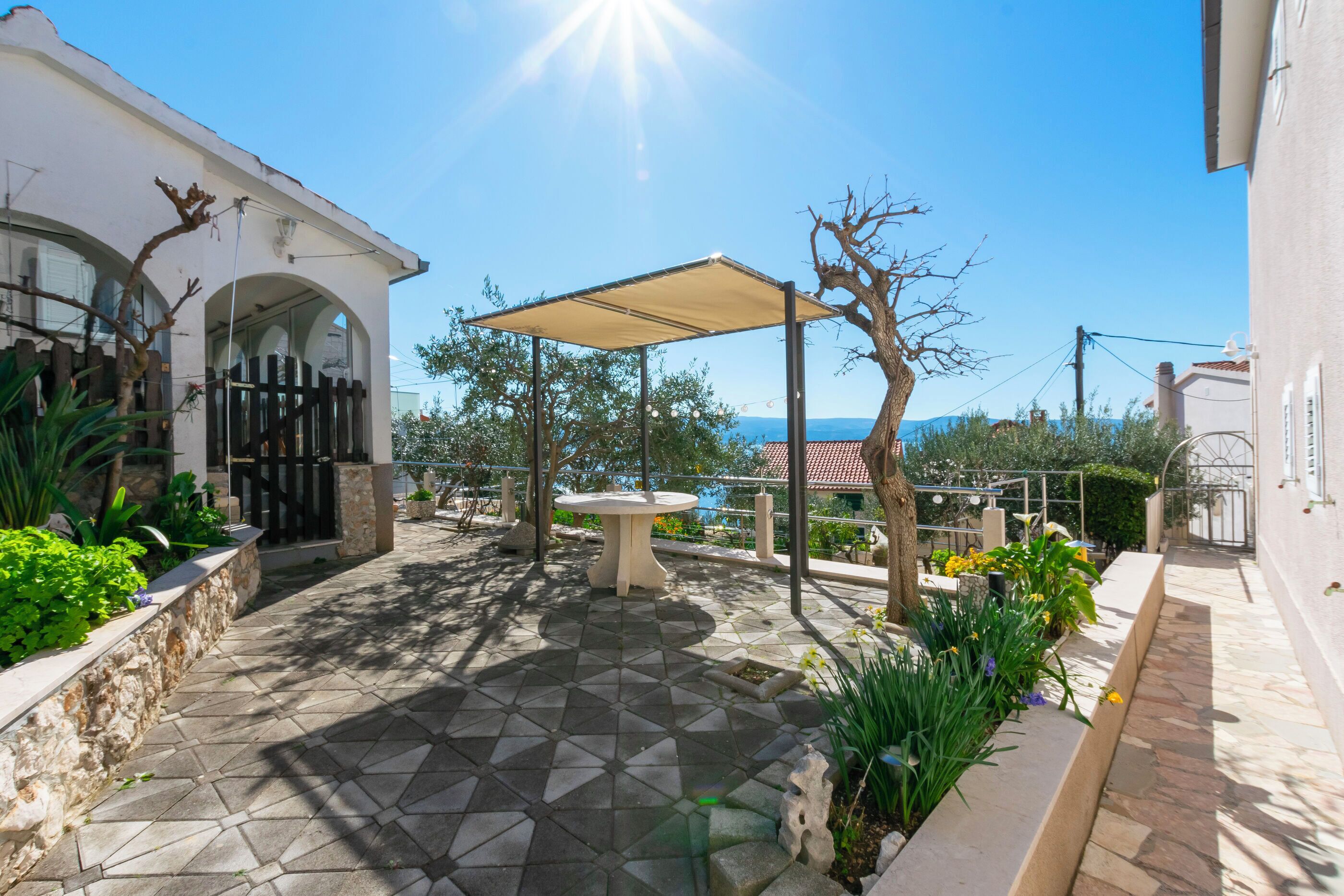 A courtyard with a tiled floor, a pergola, and a table.
