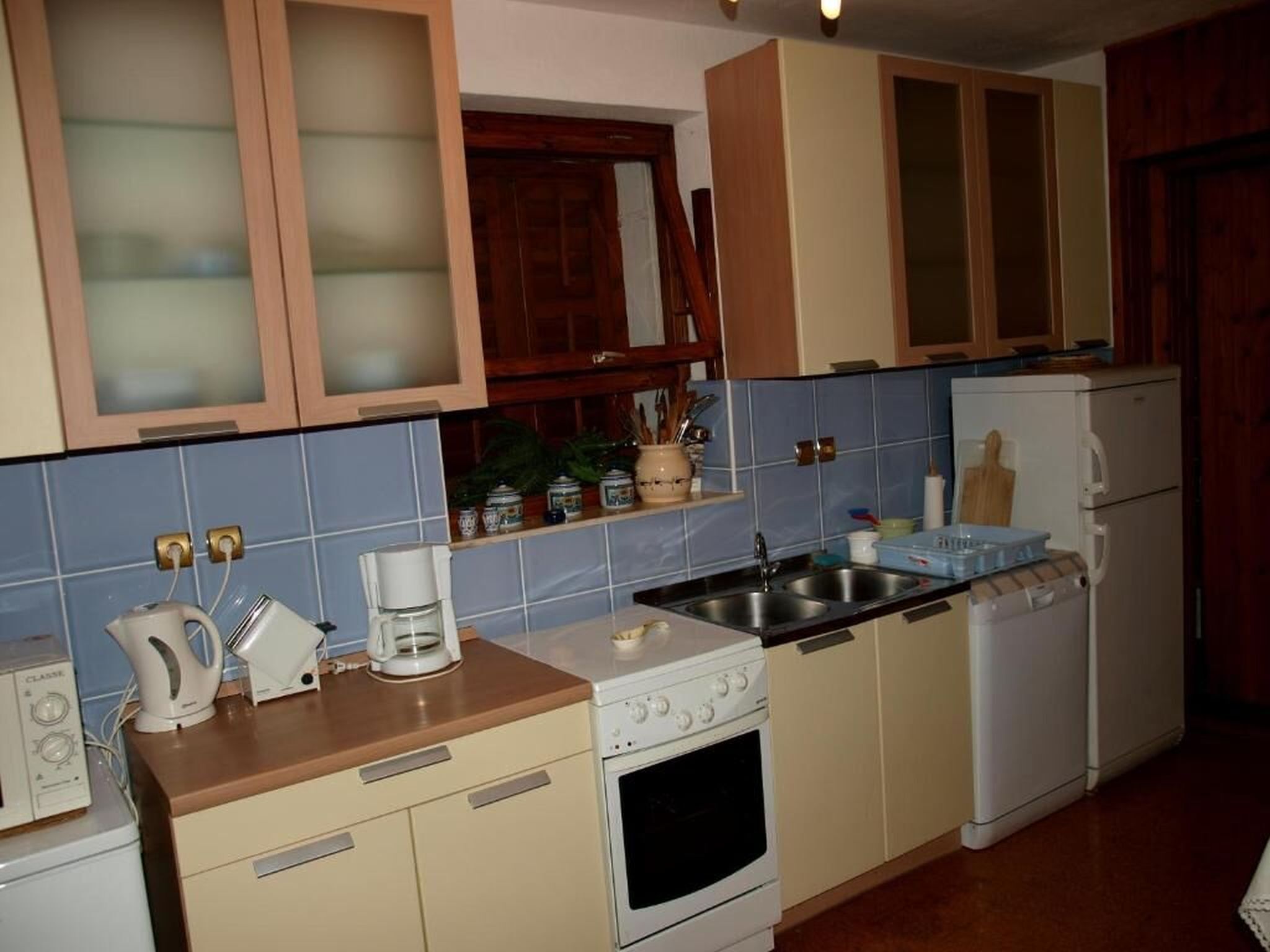 A kitchen with wooden cabinets, a stove, a sink, and a refrigerator.