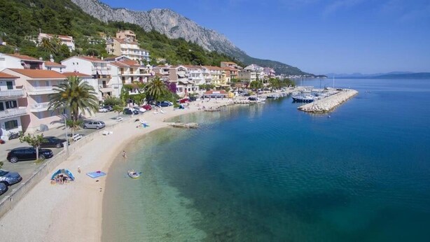 A coastal town with a sandy beach, clear blue waters, and buildings along the shore. - Apartment Haus Franciska (Podgora)