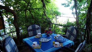 An outdoor dining area with a table set for four, surrounded by chairs with plaid cushions. - Apartment Haus Franciska (Podgora)