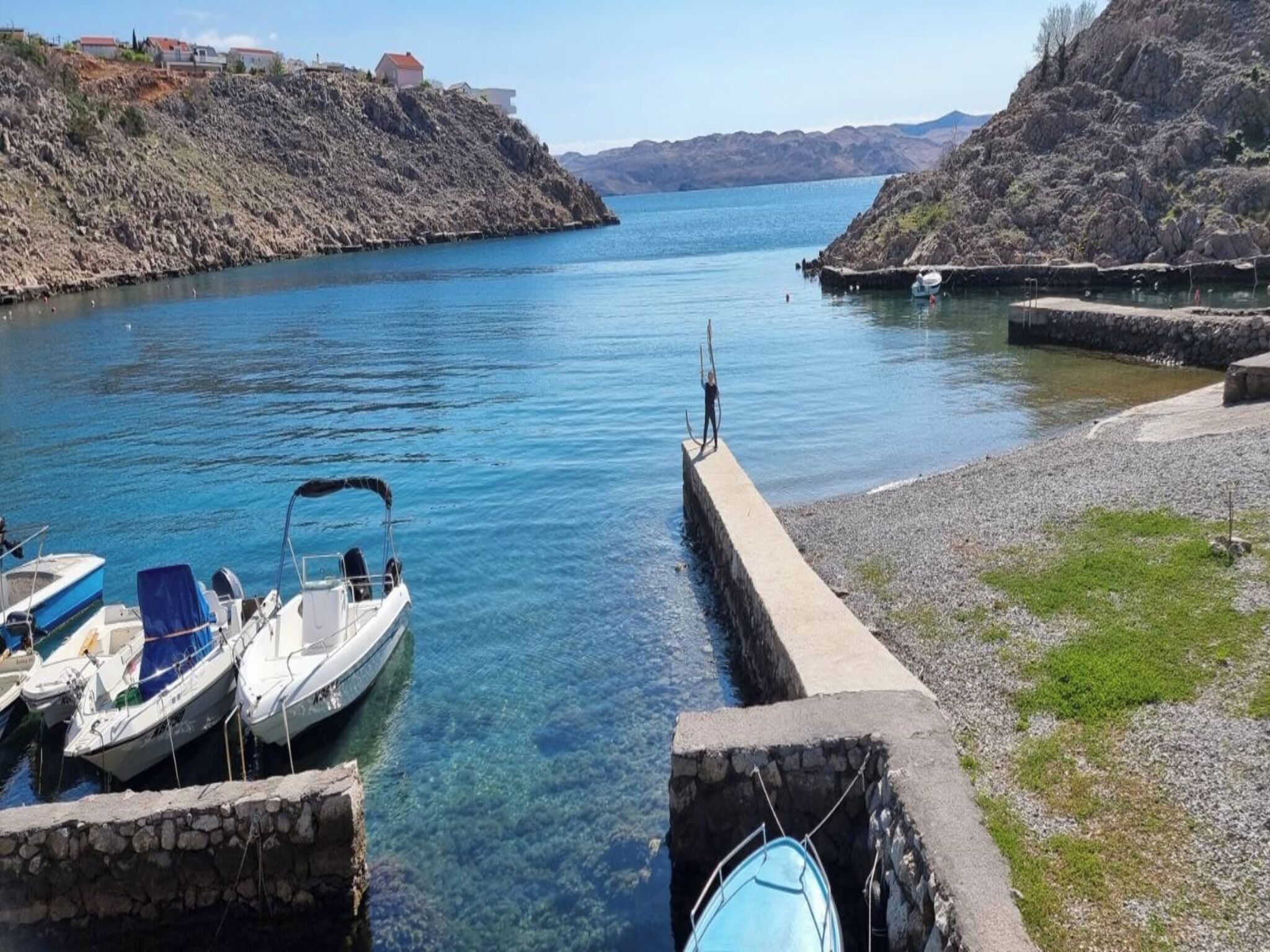 Un port où des bateaux sont amarrés, une voie navigable dégagée et, au loin, des collines rocheuses.