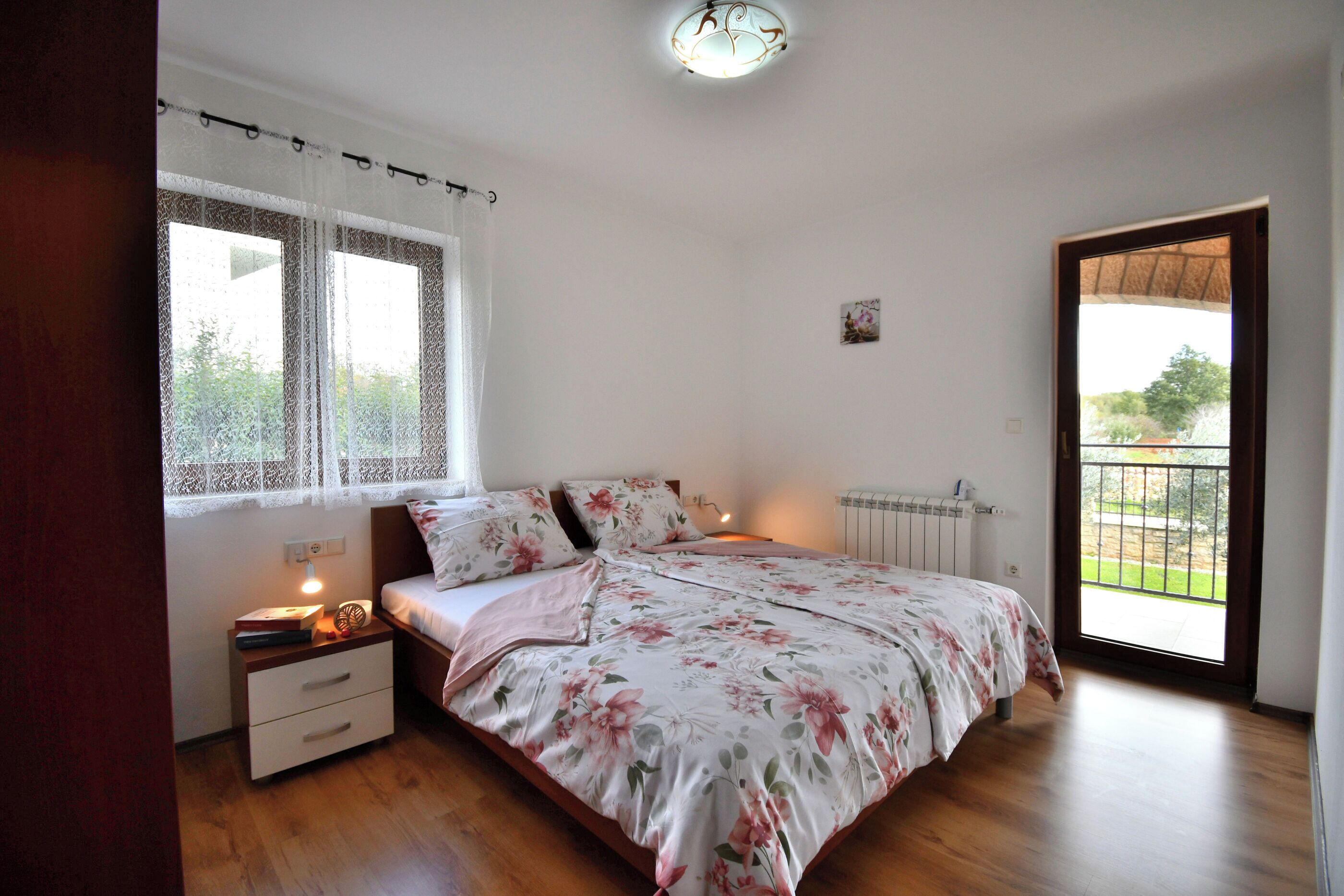 A bedroom with a bed, nightstand, and a window with curtains.
