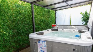 Un bain à remous doté d’un panneau de sécurité, entouré de verdure.