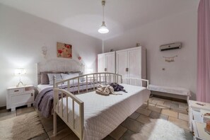 Et soveværelse med seng, natbord, garderobeskab og et lille bord med lampe.