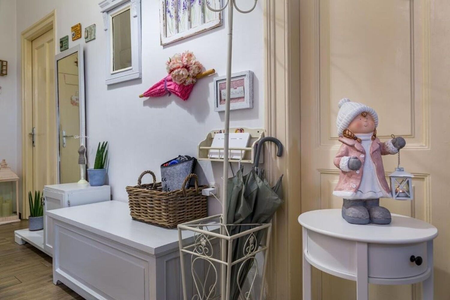A neatly organized room with a white console table, a wicker basket, a framed picture, and a decorative figure on a small pedestal.