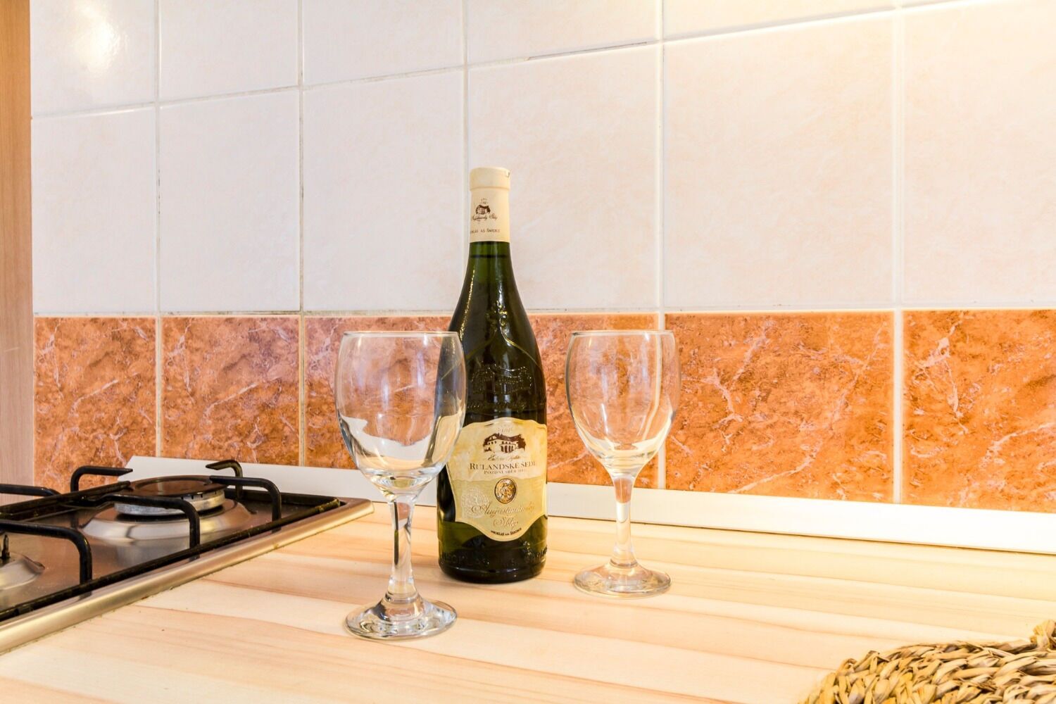 A kitchen counter with a bottle of wine and two glasses.
