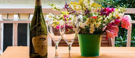 A bottle of wine, two glasses, and a potted plant on a wooden table.