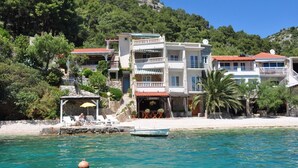 Un hotel frente al mar con varios balcones, un área de descanso en la playa y vistas al océano.