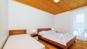 Une chambre avec deux lits, un plancher en bois et un plafond en bois.