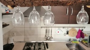 A kitchen with a gas stove, a sink, hanging glassware, and various utensils. - Apartment Dolac (Marcana)