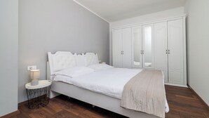 A bedroom with a bed, a bedside lamp, a wardrobe, and a round side table. - Apartment Filip 2 (Crikvenica)
