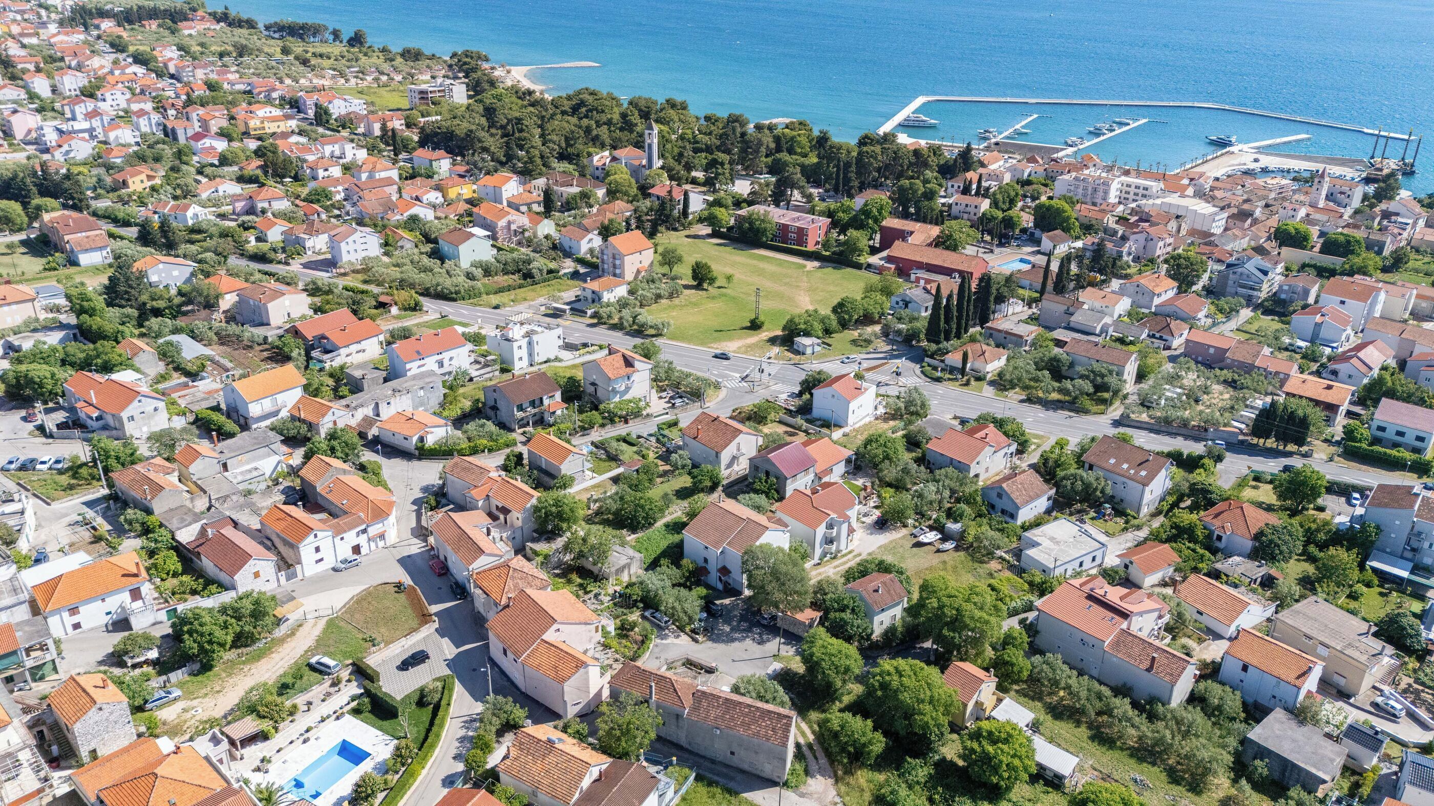 An aerial view of a coastal town with residential buildings, a marina, and a prominent church.