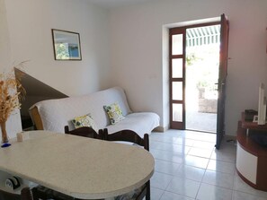 A room with a bed, a small table, and a door leading outside. - Apartments Family (Postira)