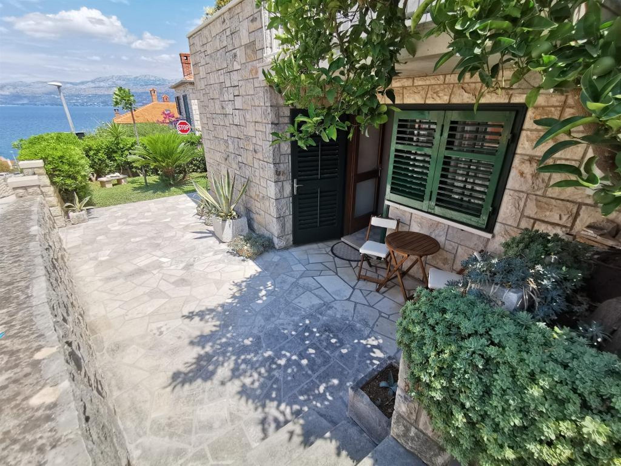 A stone building with a small patio, a wooden table, and a chair.