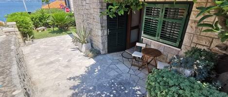 A stone building with a small patio, a wooden table, and a chair.