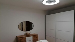 A modern bedroom with a bed, a wooden dresser, a mirror, and a wardrobe. - Apartment Vesna (Postira)