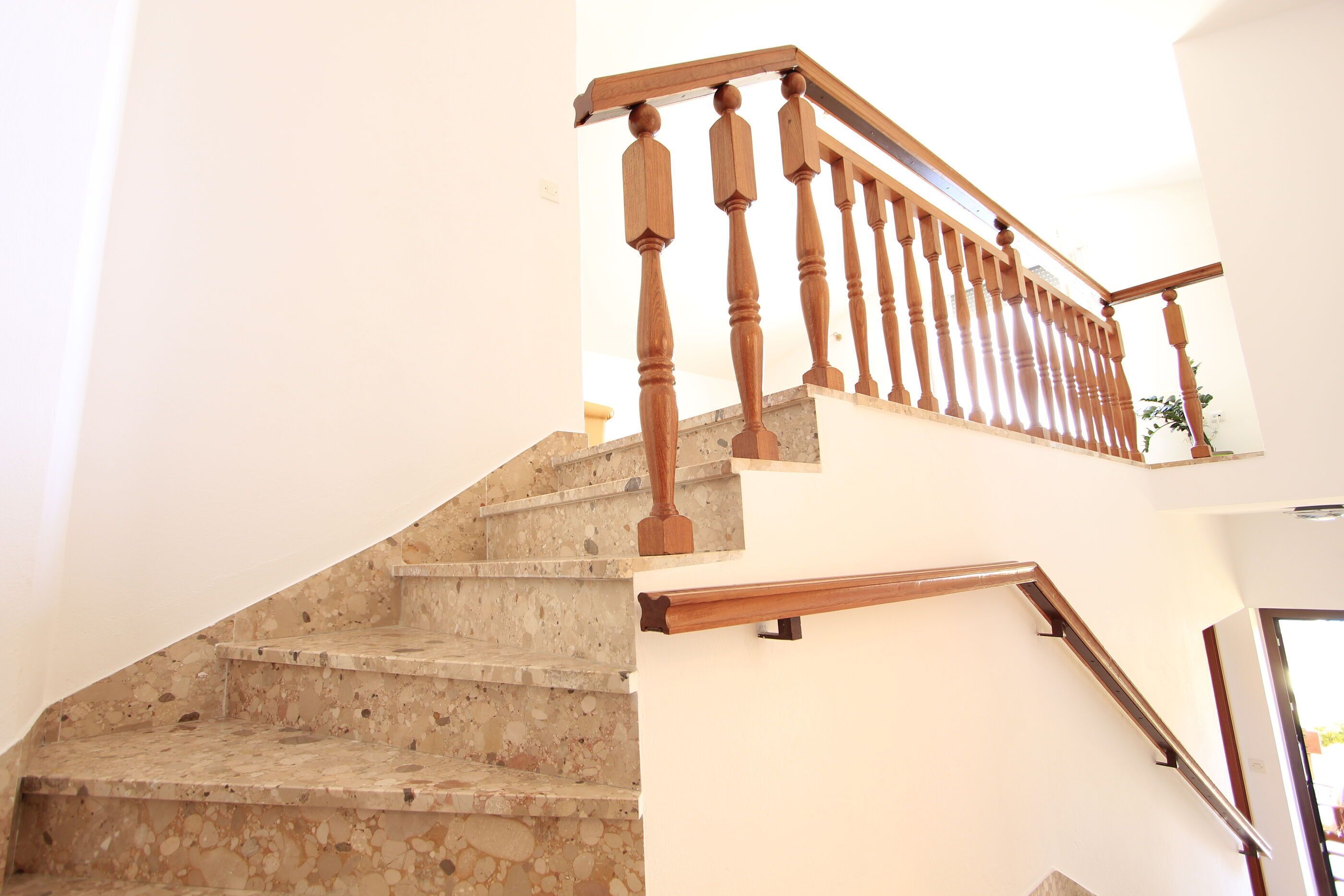 A staircase with a wooden handrail and a stone wall.