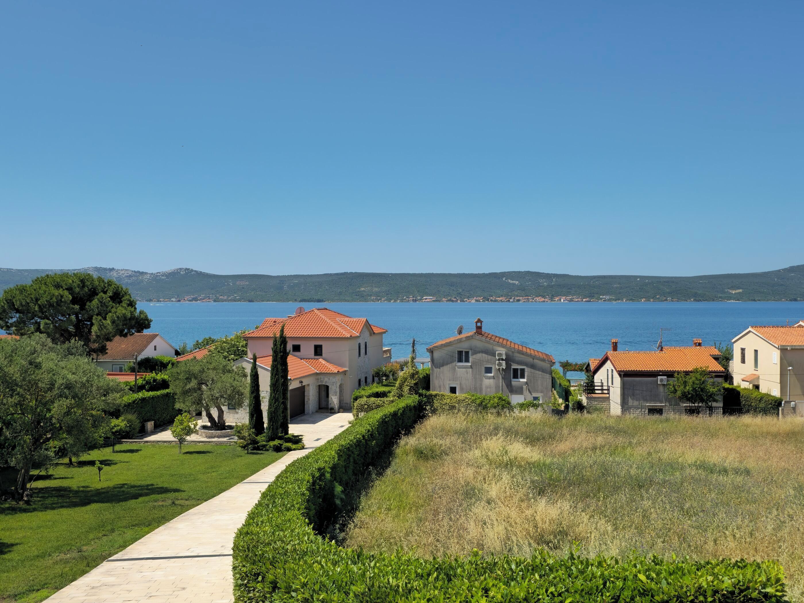 Un quartier résidentiel situé sur la côte, avec des maisons, un ciel dégagé et une vue sur la mer.