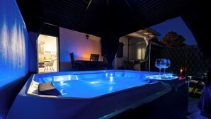 Een jacuzzi met blauw licht, een eethoek met stoelen en uitzicht op de achtertuin.