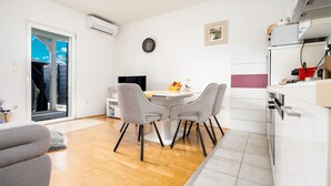 Een compacte keuken met een eethoek, een inbouwoven en een schuifpui naar een balkon.