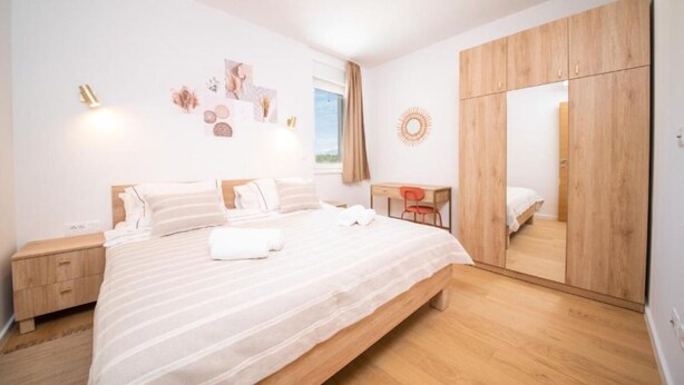 Ein modernes Schlafzimmer mit einem großen Bett, einem Holzschrank und einem Schreibtisch.