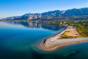 A lakeside view with a small island, clear water, and mountains in the background. - Apartment Agava (Starigrad)