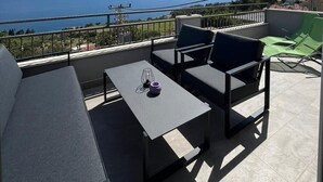 A terrace with a table and chairs, a view of the sea, and a distant landscape. - Apartments Dobrila (Jelsa)
