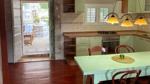 Une cuisine rustique avec des meubles en bois, une cuisinière à gaz et un coin repas comprenant une table et des chaises.
